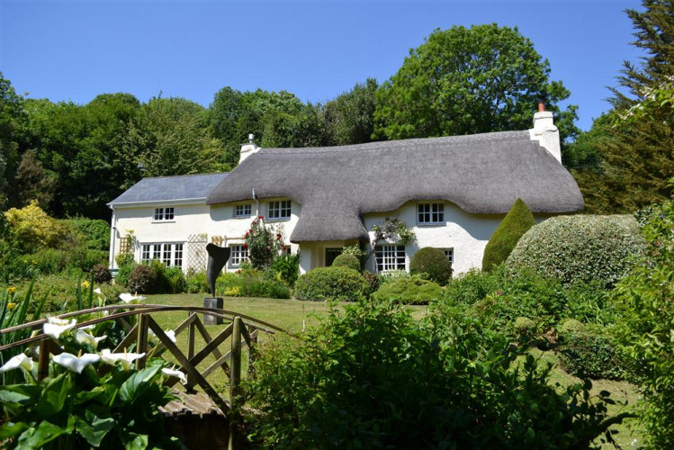Goodshelter, a beautiful Devon thatched cottage, surrounded by lovely gardens that slope down to a stream.